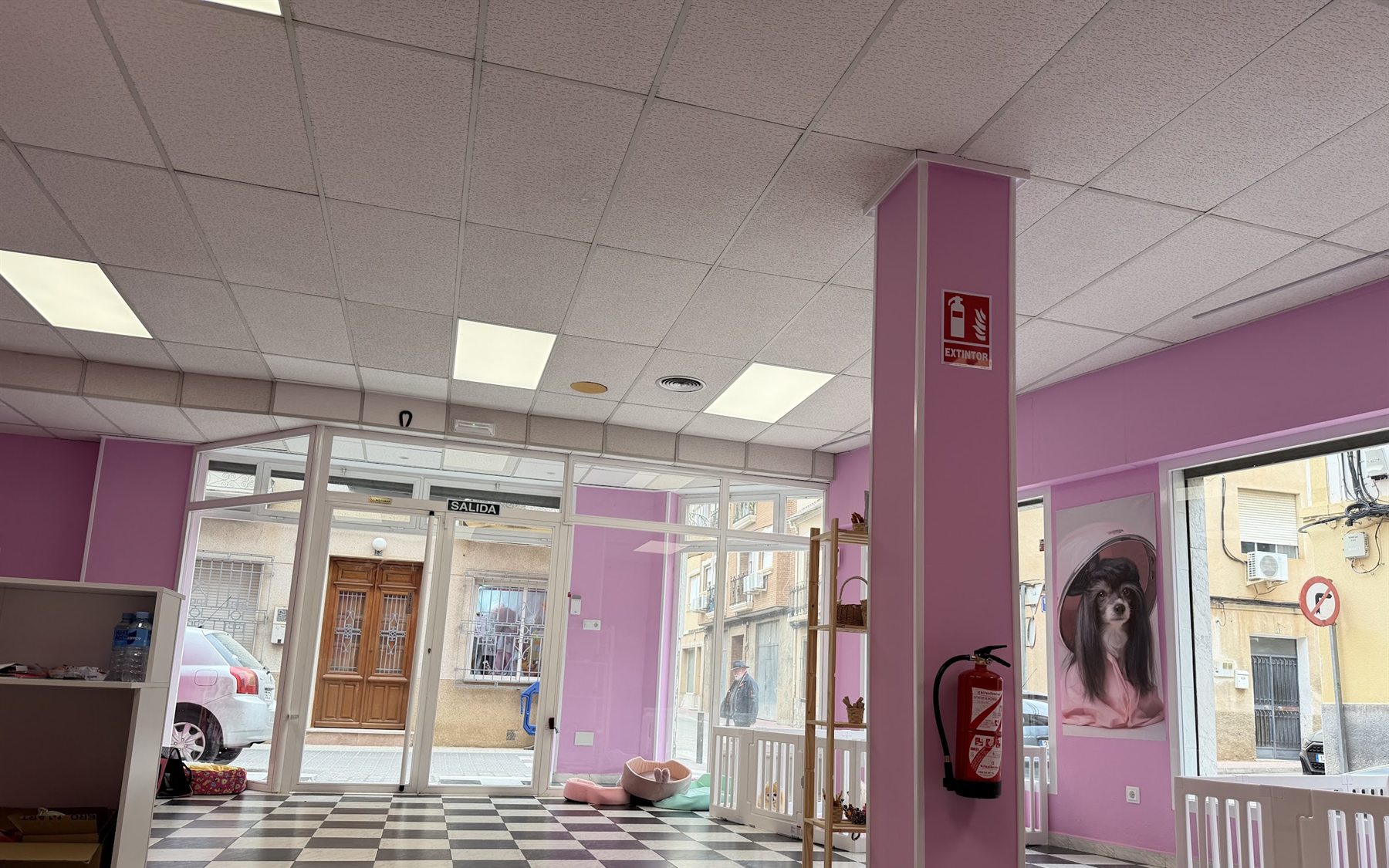 Interior del salón: paredes rosas, suelo de damero blanco y negro y escaparate a la calle